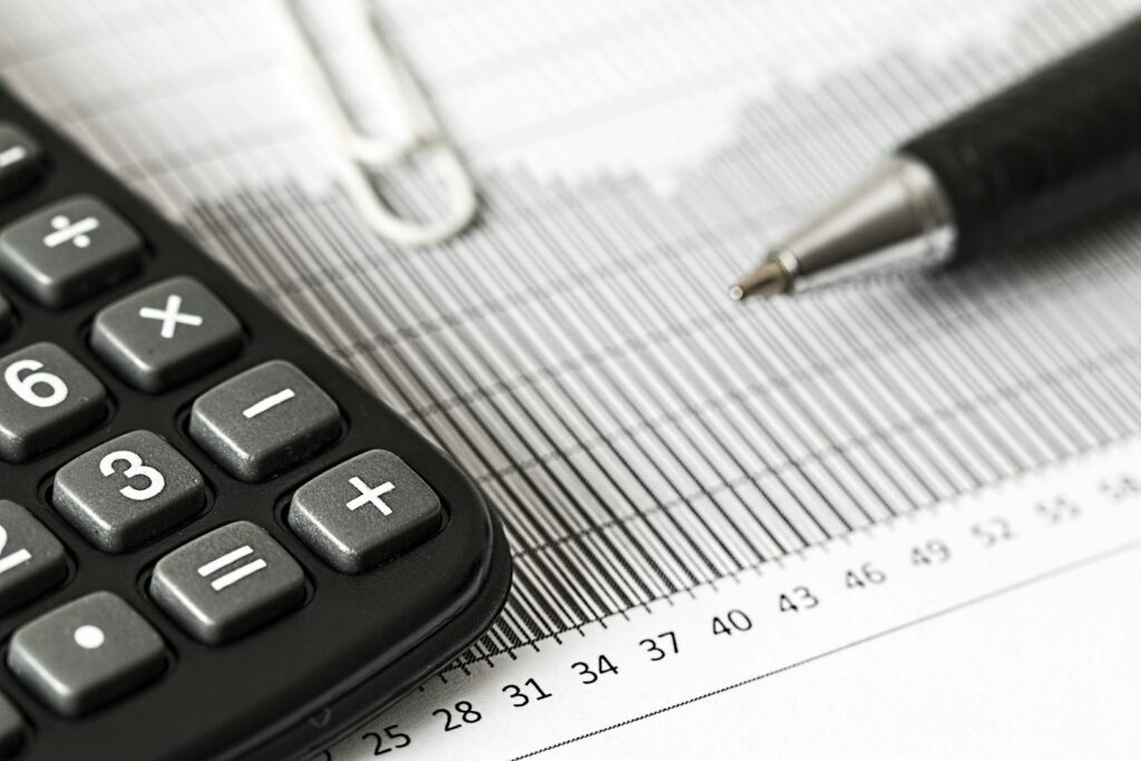 Close-up of a calculator and pen on a bar graph, representing finance and accounting.